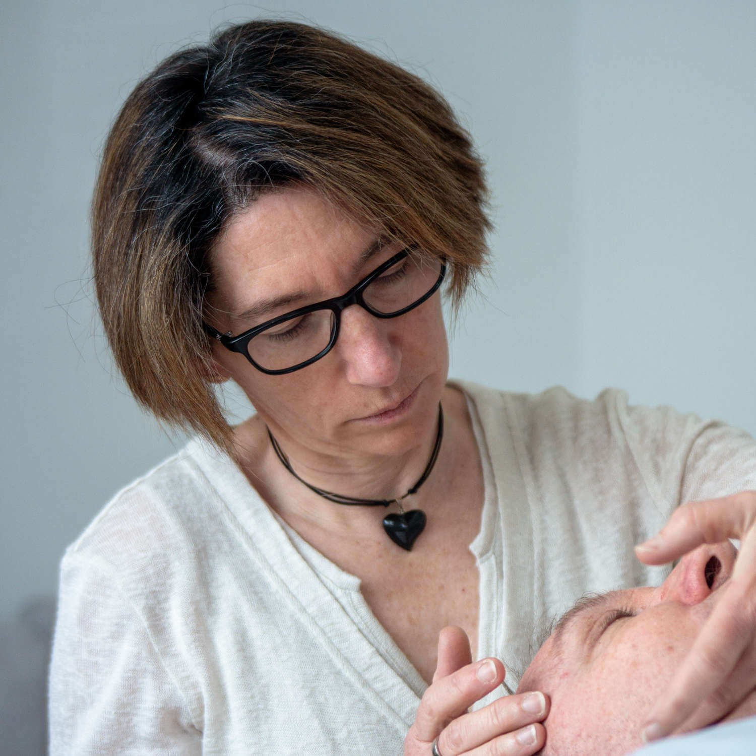 Une praticienne en ostéopathie examine avec attention le poignet d’un patient en consultation bienveillante
