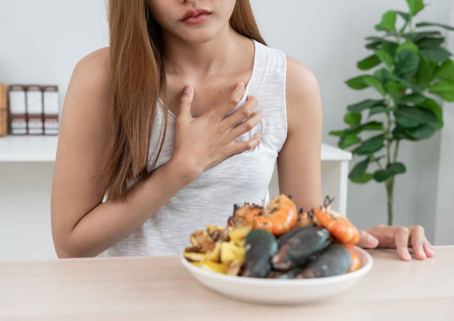 Une personne pose sa main sur sa poitrine en regardant une assiette de fruits de mer colorés